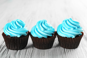 Delicious cupcakes on white wooden background, close up