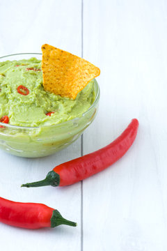 Guacamole with nachos, chili peppers 
