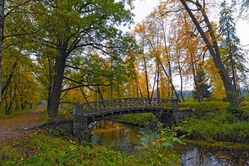 Picturesque autumn landscape with old bridge over channel