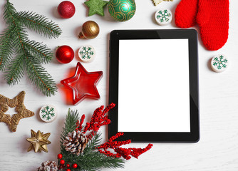 Tablet and Christmas decor on white wooden background