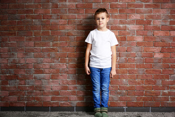 Small cute boy on brick wall background