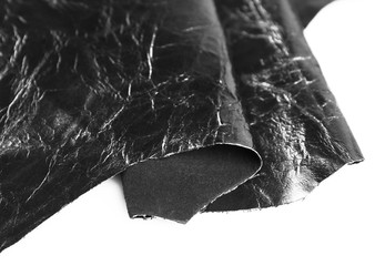 Black shiny leather texture on white background, close up