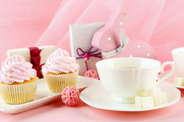 Tasty cupcakes with gifts and decorations on pink background