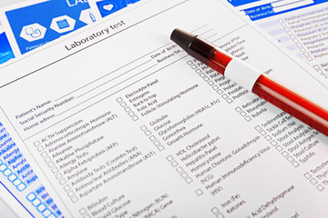 Blood in test tubes and investigation form on the table, close-up