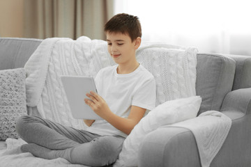 Boy using tablet on a sofa at home