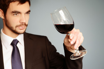 Man looking at the glass of red wine on blue background