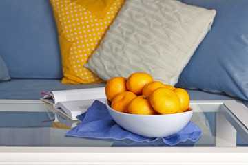Bowl with fresh tangerines on table in living room, close up