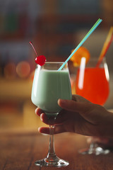 Female hand with glass of cocktail on bar background