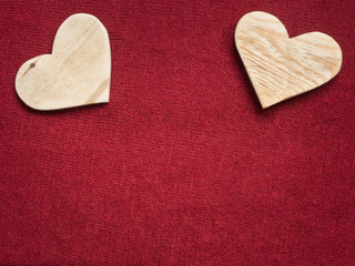 Fototapeta premium two wooden hearts on a red fabric background
