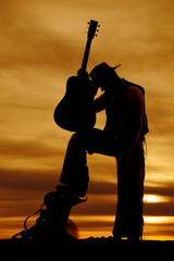 silhouette of cowboy foot on saddle guitar lean on with head