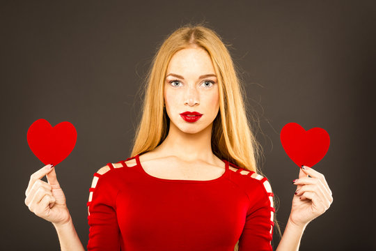 gorgeous woman with glamour bright makeup and red lips and hearts in hand