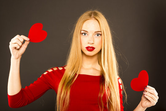 young red-haired woman holding a red heart. Beautiful makeup, red lipstick