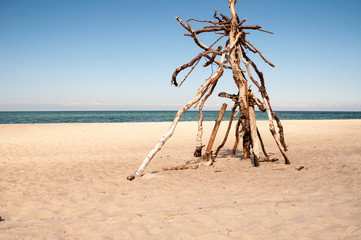 Sculpture made of driftwood on the beach at blue sky.