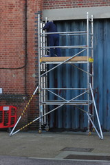 A painter and decorator working from a scaffold tower