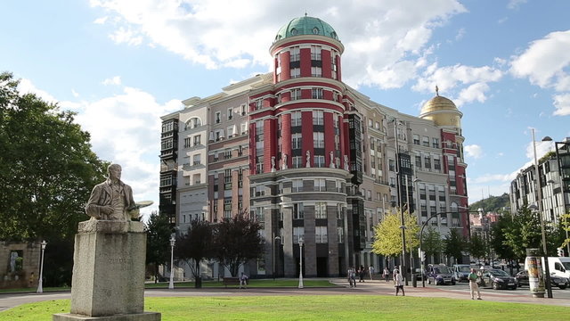 Beautiful city square with green lawns, modern buildings and historical monument