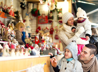 Fototapeta na wymiar Happy family choosing Christmas decoration at Christmas market