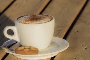 cappuccino coffee in a white cup. with cinnamone and biscuits 