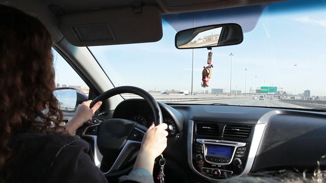 Young woman driving car with passenger near, highway ride, Russia