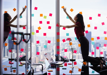 Busy Person Attaching Many Sticky Notes On Large Window - obrazy, fototapety, plakaty