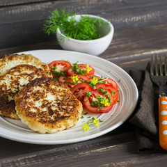 Vegetarian vegetable  cutlets and tomato salad on dark wooden background