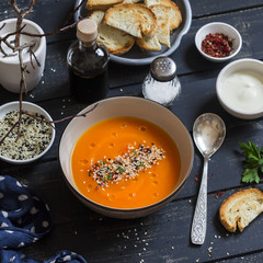Roasted pumpkin soup in a ceramic bowl on dark wooden surface