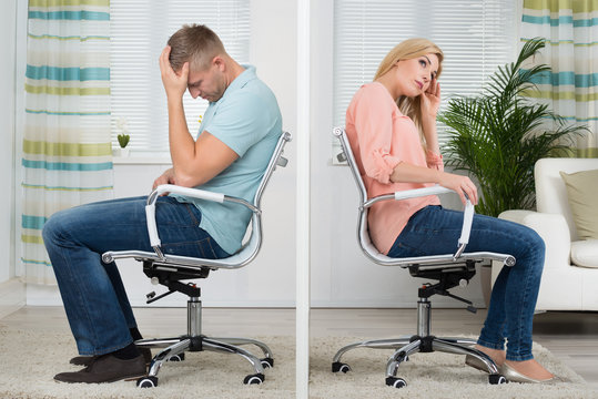 Upset Couple Sitting On Chairs At Home