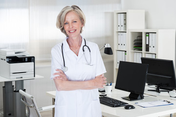 Confident Female Doctor Standing Arms Crossed In Clinic