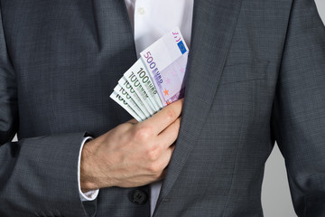 Businessman Putting Bribe In Suit Pocket