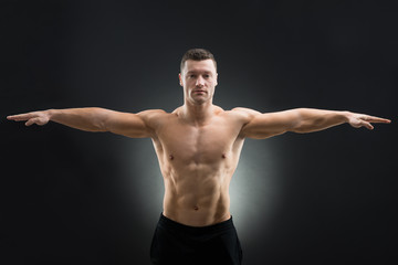 Fototapeta na wymiar Confident Muscular Man Standing Arms Outstretched