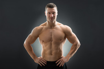 Confident Muscular Man Standing With Hands On Hip