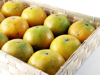 row of oranges arranged in square woven bamboo basket isolated on white