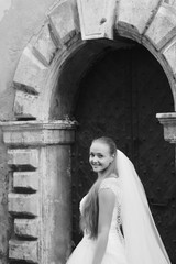 Smiling with her heart. Monochrome vertical shot of a happy beautiful bride wandering around an old city