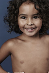 Happy young shirtless boy in blue studio