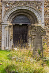 Fototapeta na wymiar Ancient church door made of wood with celtic cross headstone