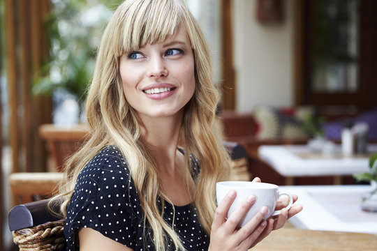 Young blonde woman enjoying coffee in cafe