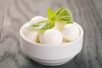 small balls of mozzarella in bowl with basil