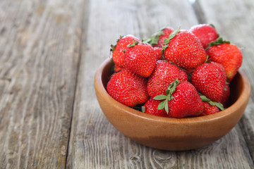 Ripe strawberries in a brown bowl