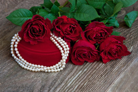 Red  gift box and necklace  on  wooden background.  Valentine's day, wedding or birthday  concept