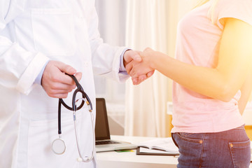 Young attractive doctor shaking hand of his patient