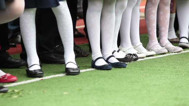 Feet of schoolgirls in white pantyhose. Kids standing in line. September, 1 in Russia