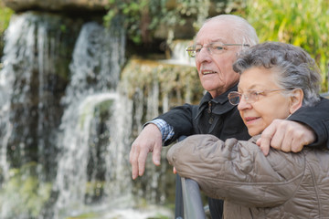elderly couple next to a waterfalls