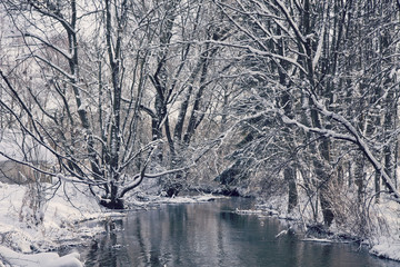 Bavarian idyllic winter landscape with river, trees and snow