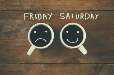 coffee cup with sad and happy faces next to "friday saturday" phrase background. vintage filtered. happy weekend concept