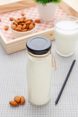 Almond milk in glass bottle with almonds