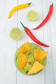 Guacamole with nachos, chili peppers and lime
