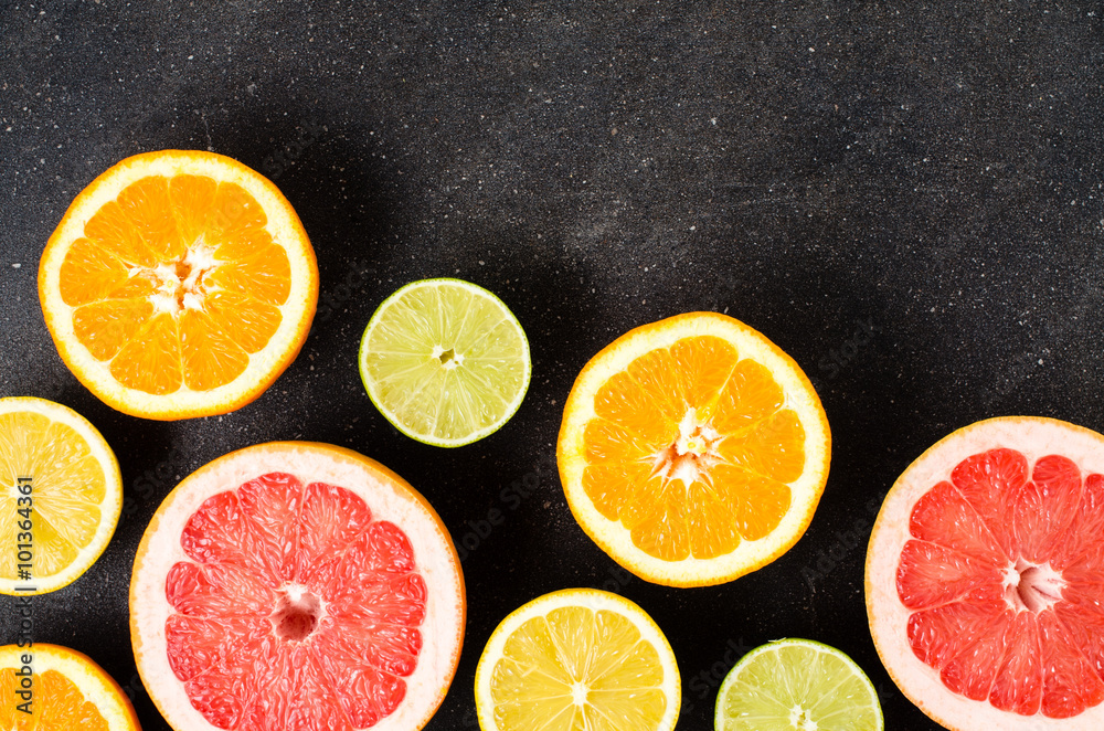 Wall mural Mix of citrus fruits on dark table