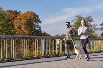 Obraz premium happy couple with dog running outdoors