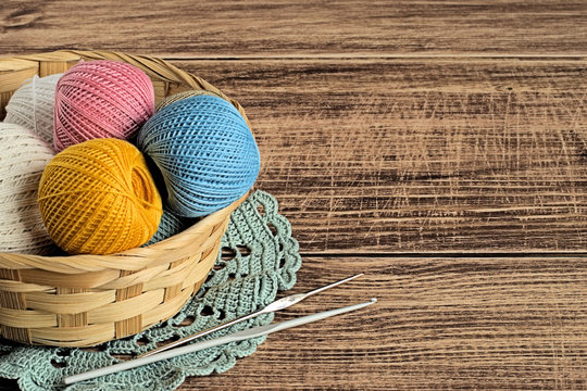Yarn.  Balls of colored cotton yarn in a basket on a brown wooden background.