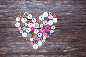 Colorful buttons heart on old wooden background