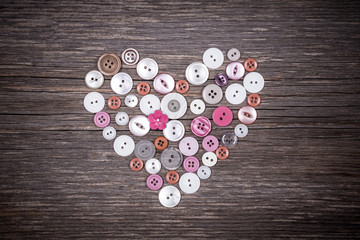 Colorful buttons heart on old wooden background
